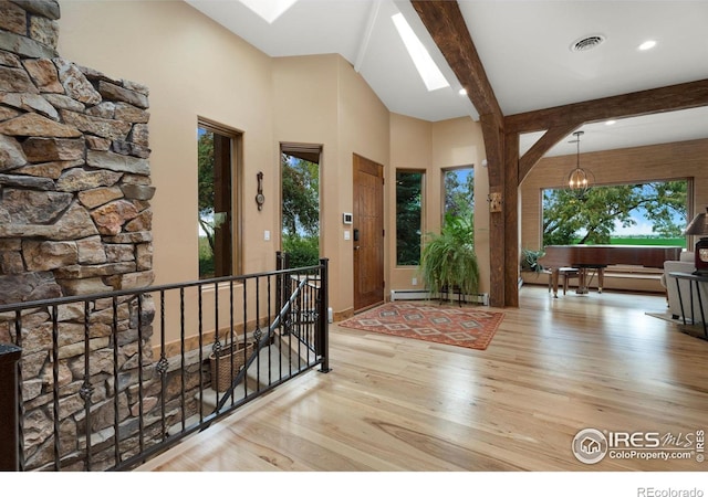 foyer entrance with a baseboard radiator, a wealth of natural light, light hardwood / wood-style flooring, and beam ceiling