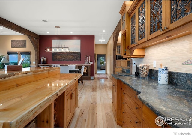 kitchen with wooden counters, light hardwood / wood-style floors, sink, hanging light fixtures, and beam ceiling