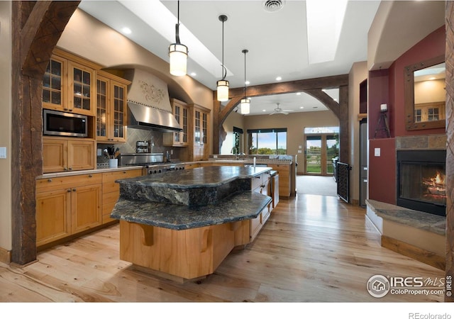 kitchen featuring stainless steel microwave, ceiling fan, a kitchen bar, a large island, and range