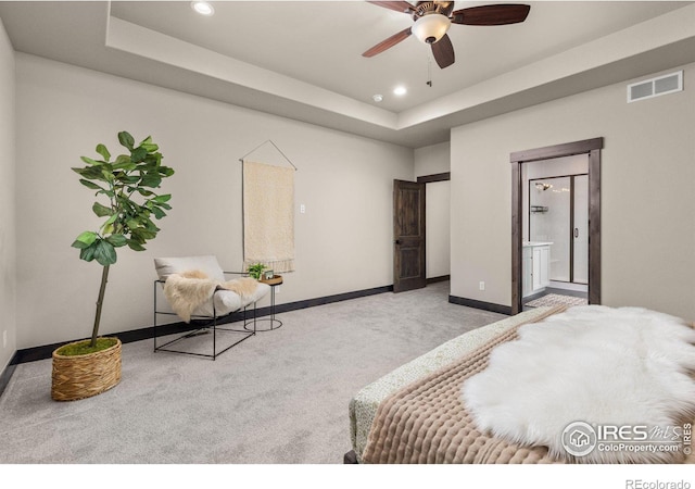 carpeted bedroom with ceiling fan, ensuite bathroom, and a raised ceiling