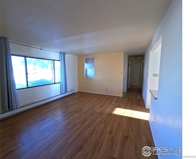 empty room with baseboard heating and wood-type flooring