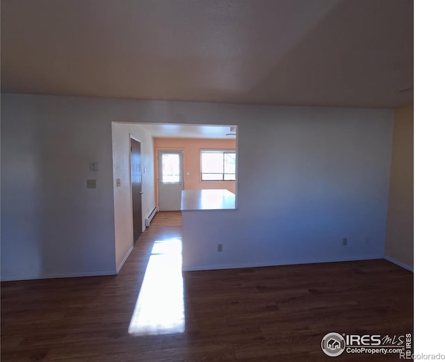 empty room featuring baseboard heating and dark hardwood / wood-style flooring