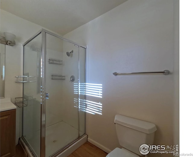 bathroom with toilet, a shower with shower door, wood-type flooring, and vanity