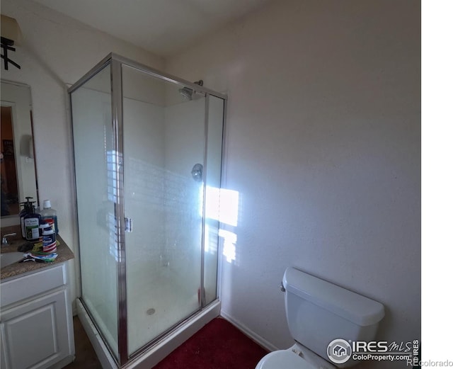 bathroom featuring a shower with shower door, toilet, and vanity