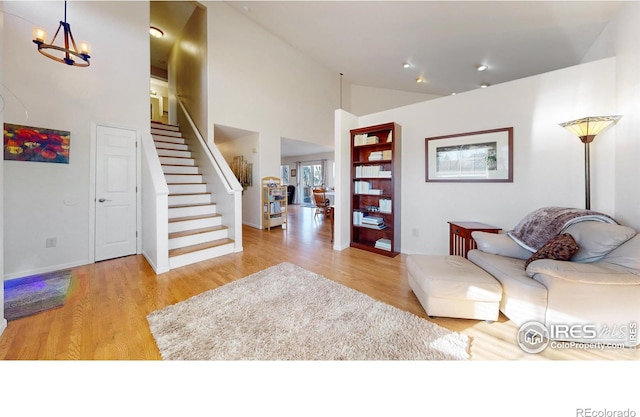 living room featuring high vaulted ceiling, light hardwood / wood-style flooring, and an inviting chandelier