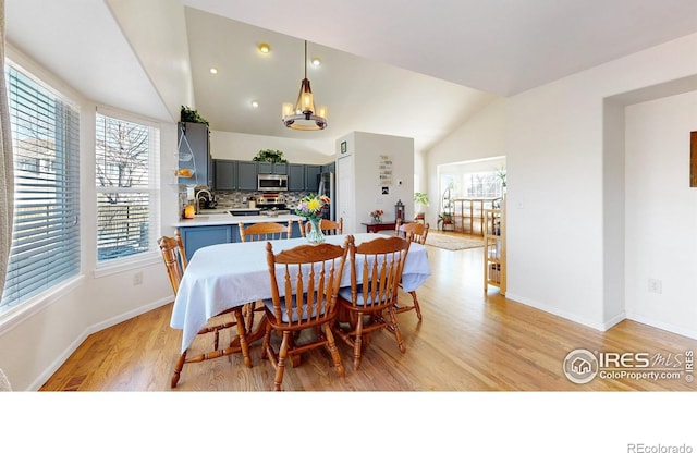 dining area with vaulted ceiling, an inviting chandelier, light hardwood / wood-style floors, and plenty of natural light