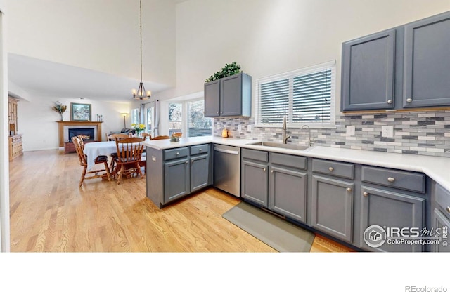 kitchen with tasteful backsplash, dishwasher, pendant lighting, kitchen peninsula, and sink