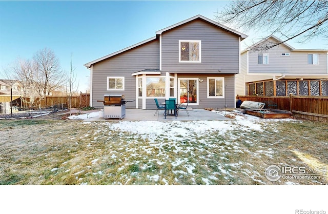 snow covered house featuring a lawn and a patio