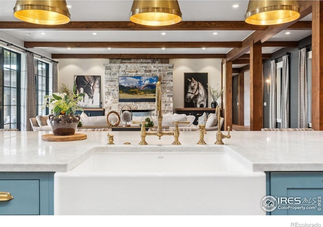 interior space featuring beam ceiling, blue cabinetry, a fireplace, and open floor plan