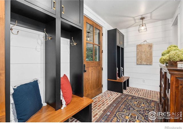 mudroom with brick floor and wooden walls