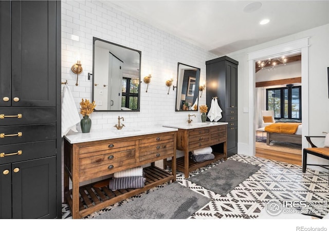 ensuite bathroom featuring a sink, decorative backsplash, two vanities, and connected bathroom