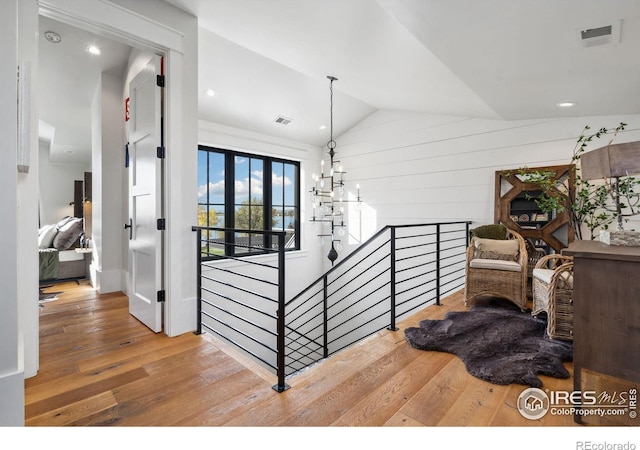 stairs featuring visible vents, lofted ceiling, an inviting chandelier, and wood-type flooring