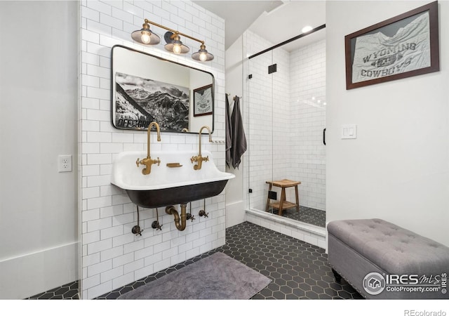 bathroom featuring tile patterned floors, tile walls, a stall shower, and a sink