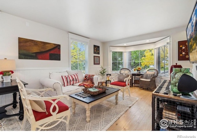 living area with wainscoting, a healthy amount of sunlight, and hardwood / wood-style floors