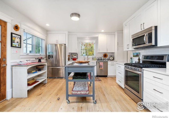 kitchen featuring tasteful backsplash, appliances with stainless steel finishes, white cabinetry, and light wood-type flooring