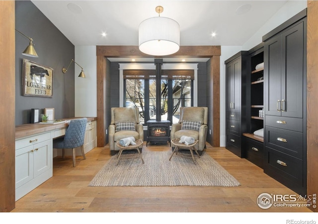 living area with recessed lighting, light wood-type flooring, a wood stove, and built in desk