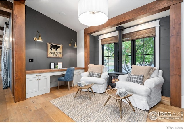 office featuring vaulted ceiling with beams, built in study area, a wood stove, and light wood-style floors