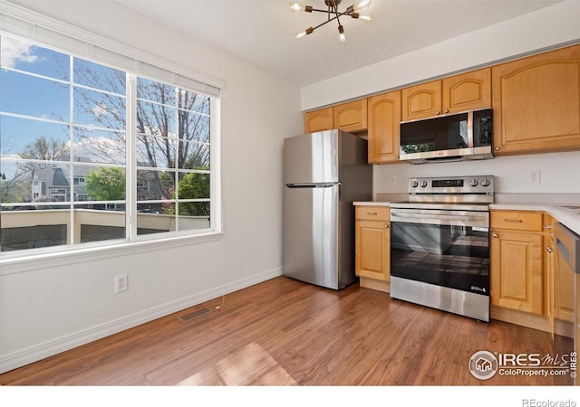 kitchen featuring light wood-style floors, visible vents, light countertops, an inviting chandelier, and stainless steel appliances