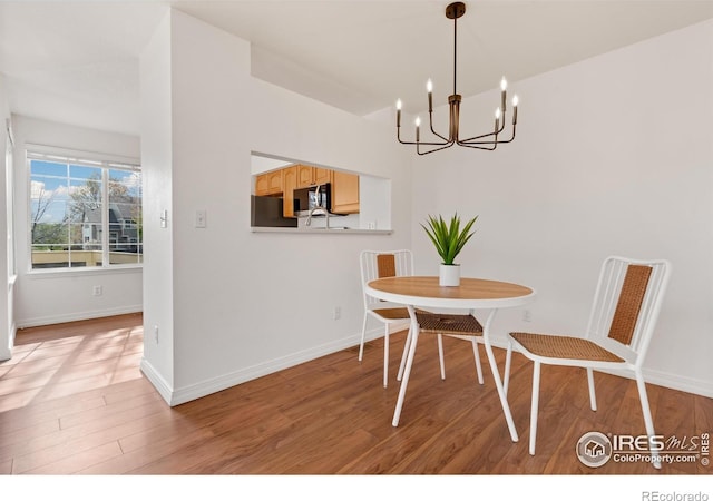dining room with baseboards, an inviting chandelier, and light wood-style floors