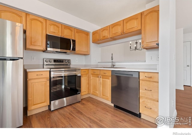 kitchen featuring light countertops, stainless steel appliances, a sink, and light wood-type flooring
