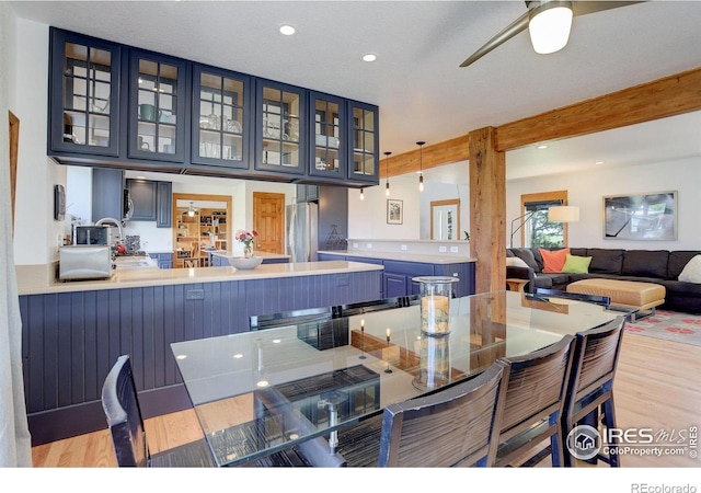 dining space with beam ceiling, light wood-type flooring, and ceiling fan