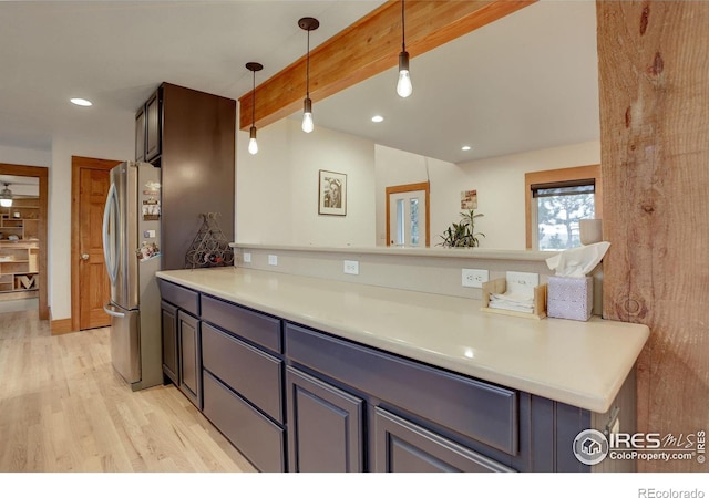 kitchen featuring pendant lighting, stainless steel fridge, beamed ceiling, and light wood-type flooring