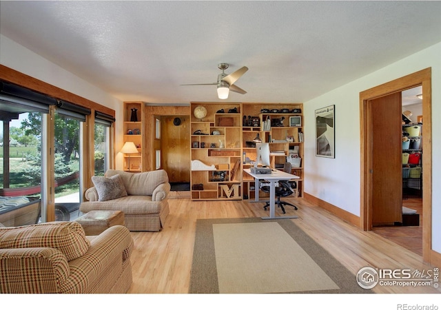 living room with ceiling fan, built in features, a textured ceiling, and light hardwood / wood-style flooring