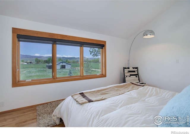 bedroom featuring lofted ceiling, a mountain view, and hardwood / wood-style flooring