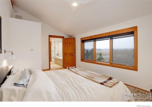 bedroom featuring ensuite bathroom and lofted ceiling