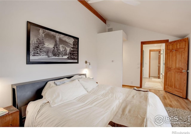 bedroom featuring light wood-type flooring and vaulted ceiling with beams