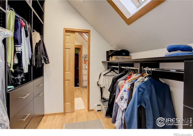 walk in closet with baseboard heating, lofted ceiling, and light hardwood / wood-style flooring