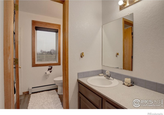 bathroom featuring toilet, vanity, and a baseboard radiator