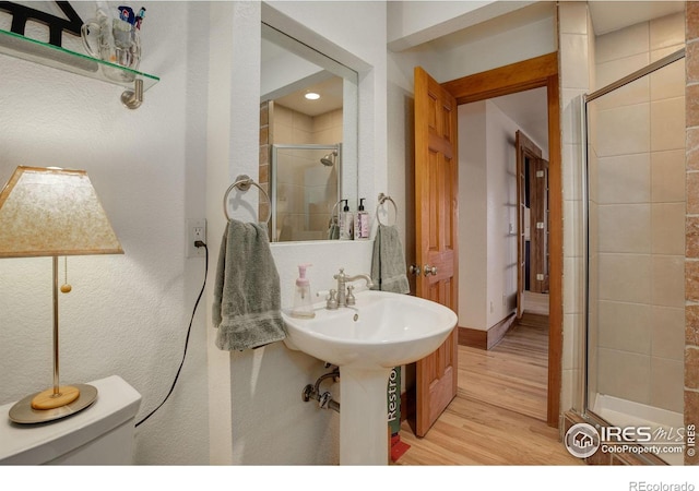 bathroom featuring hardwood / wood-style floors, toilet, and walk in shower