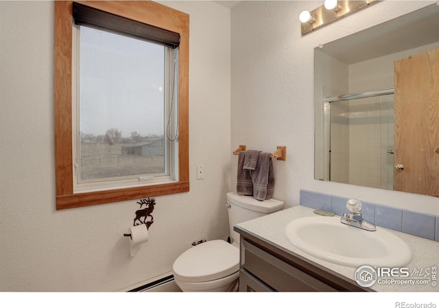 bathroom with toilet, vanity, a baseboard heating unit, and a shower with door