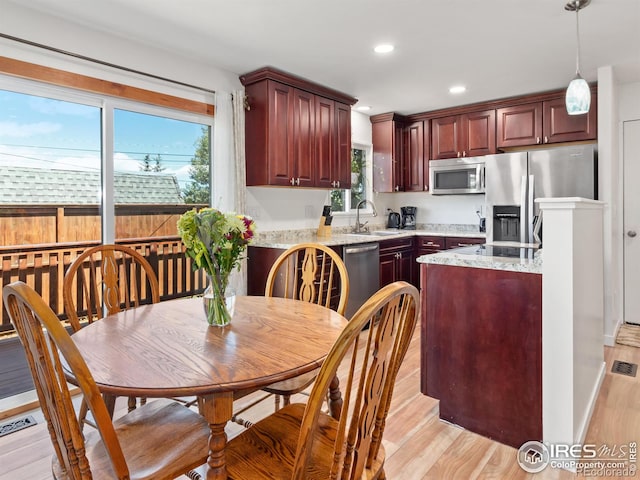 kitchen with appliances with stainless steel finishes, sink, a wealth of natural light, and light hardwood / wood-style flooring