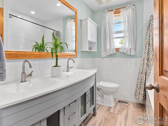 bathroom featuring vanity, toilet, and tile walls