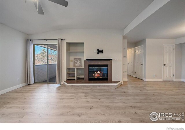 770 Copper Ln Unit 206, Louisville, CO 80027 - unfurnished living room featuring ceiling fan, light wood-type flooring, lofted ceiling, a tile fireplace, and built in shelves