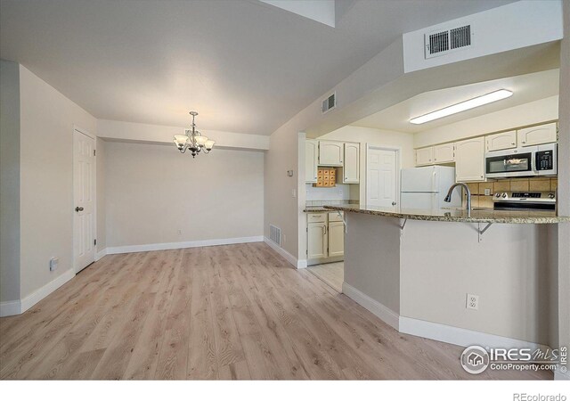 770 Copper Ln Unit 206, Louisville, CO 80027 - kitchen with a notable chandelier, kitchen peninsula, white cabinetry, stainless steel appliances, and light stone counters