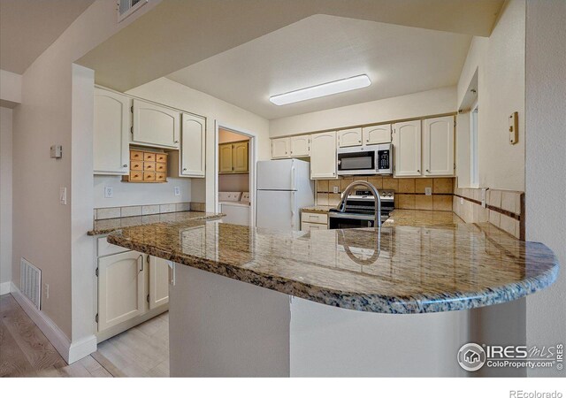 770 Copper Ln Unit 206, Louisville, CO 80027 - kitchen featuring kitchen peninsula, white cabinetry, light wood-type flooring, appliances with stainless steel finishes, and dark stone counters