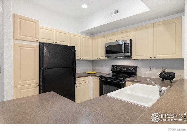 kitchen featuring black appliances, sink, and cream cabinets