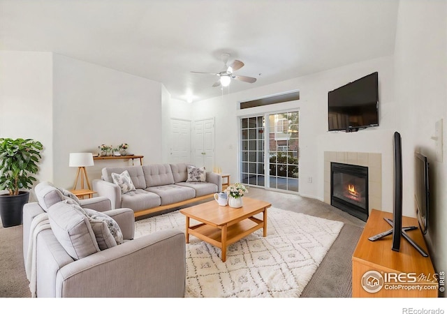 living room with ceiling fan, light colored carpet, and a tiled fireplace