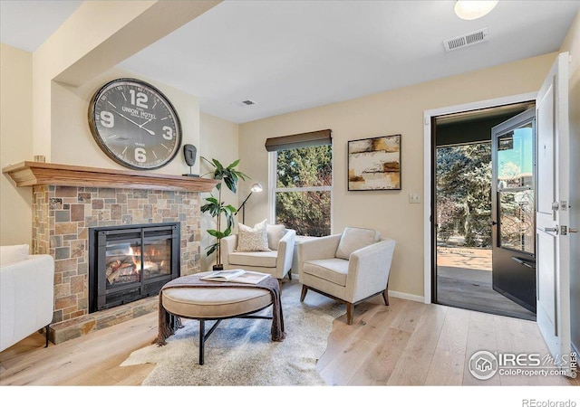 living room featuring light wood-type flooring, a wealth of natural light, and a fireplace