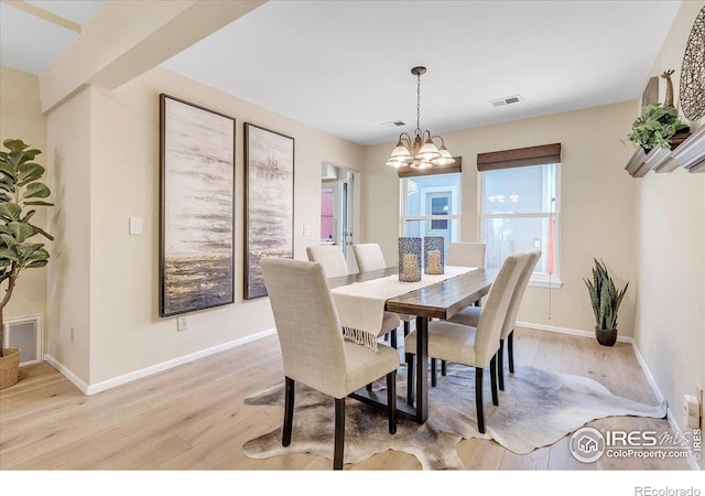 dining area with light wood-type flooring and an inviting chandelier