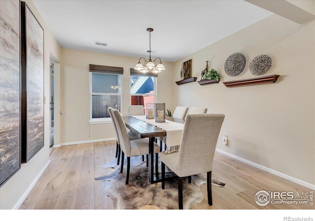 dining space with an inviting chandelier and light hardwood / wood-style floors