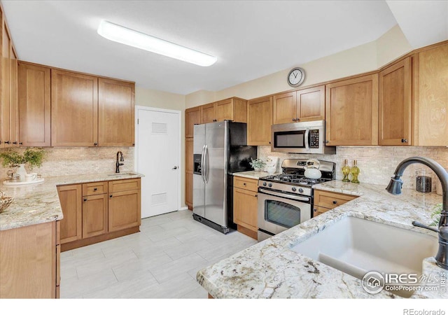 kitchen featuring light stone countertops, stainless steel appliances, and sink