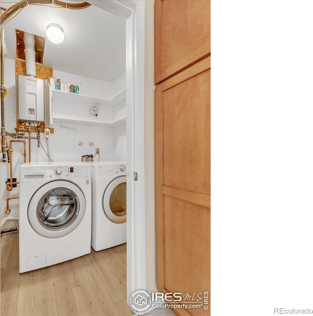 clothes washing area featuring separate washer and dryer, light hardwood / wood-style flooring, and water heater