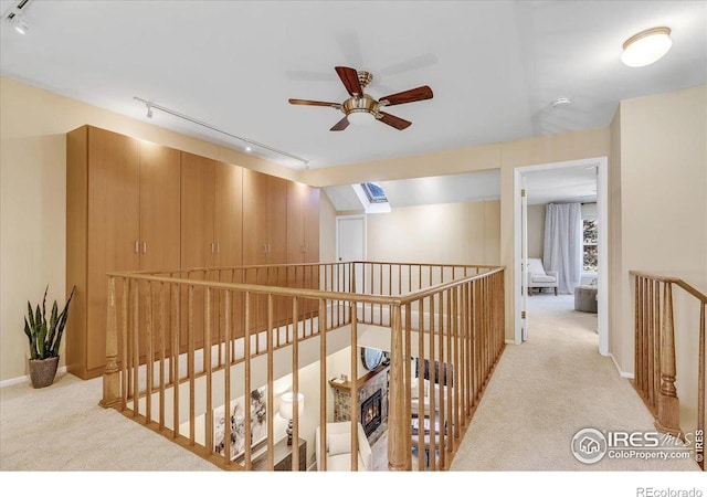 hallway featuring light colored carpet and rail lighting