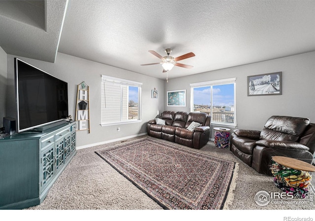 living room featuring a textured ceiling, ceiling fan, and carpet