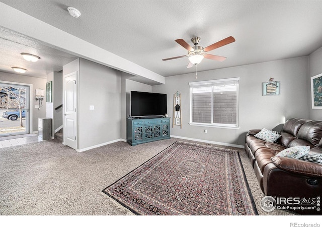 carpeted living room featuring ceiling fan and a textured ceiling