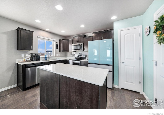 kitchen with appliances with stainless steel finishes, sink, dark hardwood / wood-style floors, and a center island